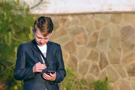 A boy with a smartphone reads a message in a smartphoneの写真素材