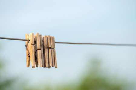 Wooden clothespins hanging on a steel wire on a light background