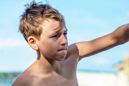 The boy is engaged in boxing on the beach, on the beach. Beats the pear with his fistの写真素材