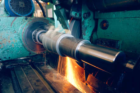Processing of metal on a grinding machine with sparks, at an industrial plant.