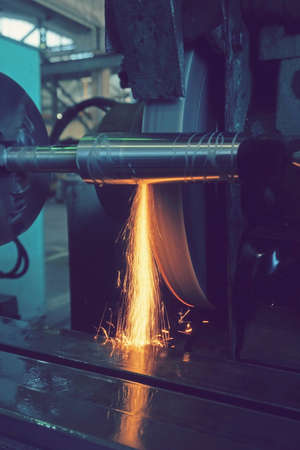 Grinding the shaft on the machine with sparks and cooling, at different anglesの写真素材