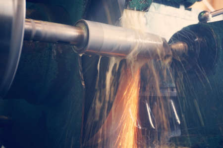 Grinding the shaft on the machine with sparks and cooling, at different anglesの写真素材