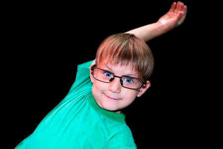 Casual boy in glasses shows different faces to the camera on a dark background