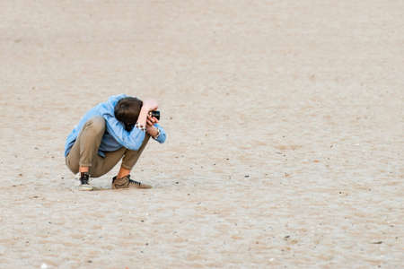 A photographer in the sand takes a picture of sittingの写真素材