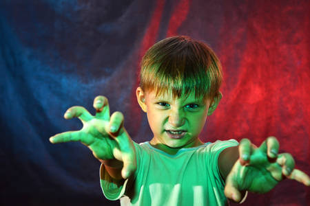 The angry boy shows his hand in front with a red-blue backlight. Studio shootingの写真素材