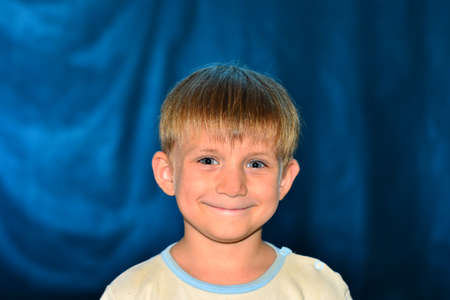 Portrait of a small, kind and happy boy with color illumination, studio shootingの写真素材