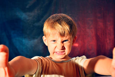 Portrait of an angry boy with a red-blue backlight.の写真素材