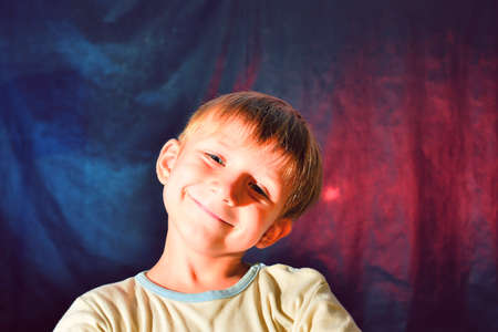 Portrait of a small, kind and happy boy with color illumination, studio shootingの写真素材