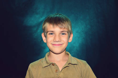 Portrait of a small, kind and happy boy with color illumination, studio shootingの写真素材