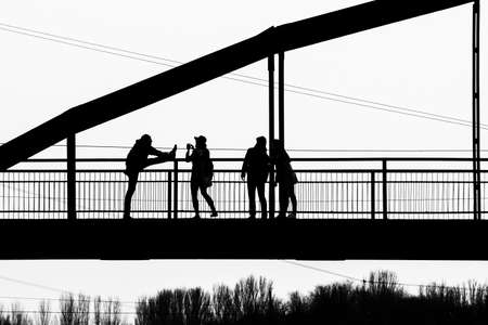 Silhouettes of people on the bridge posing with different poses for the photographer.の写真素材