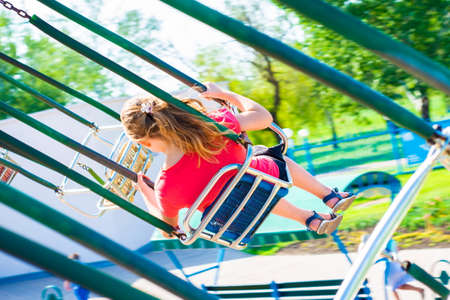 The girl is riding a carousel at high speed on a swing.の写真素材