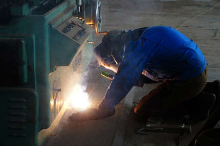 The welder at the industrial plant makes the connection using an electric arc.