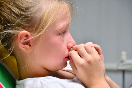 A little girl at the dentist is crying with tears at a doctor's appointment while treating a tooth.の写真素材