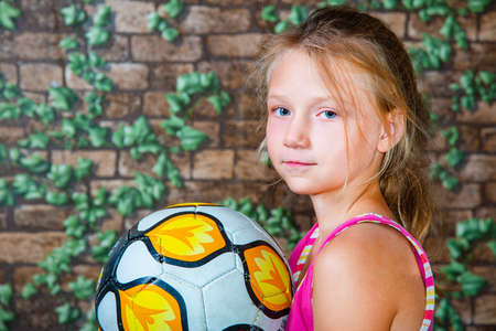 The girl is holding a soccer ball and looking into the camera.の写真素材
