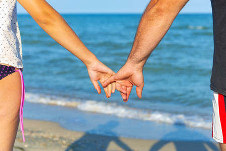 A man holds a woman by the hand on the beach by the seaの写真素材