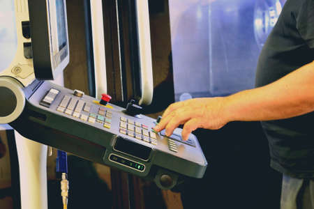 Worker, operator of the control panel of the program of operation of a high-precision CNC machining center, processing the manufacturing process of a metal product at the factoryの写真素材