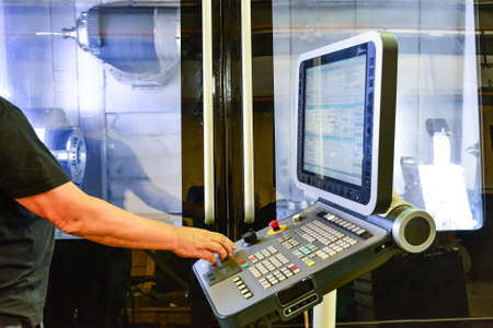 Worker, operator of the control panel of the program of operation of a high-precision CNC machining...