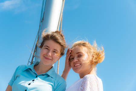 Beautiful and joyful girls, smiling friends, on the deck of a yacht