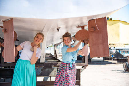 The girl stands under the ship and clings to the screws of the ship in the dock
