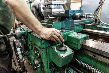 The worker, the man, makes mechanical actions of the machine control. Turning work in production