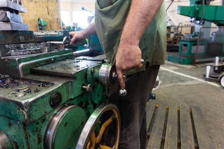 Worker, a man processes metal products on a machine. Turning work in production