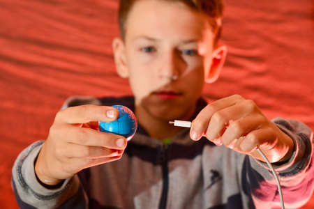 A man is trying to charge the planet earth from the network, through a white cable on a red background. The concept of saving the planetの写真素材