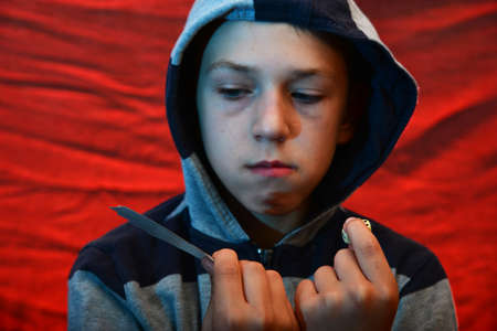 Playing and playing cards in the hands of a man with a hood on a red background.
