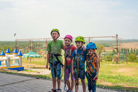 Four children are wearing helmets and climbing clothes and are ready to overcome obstacles in an extreme parkの写真素材