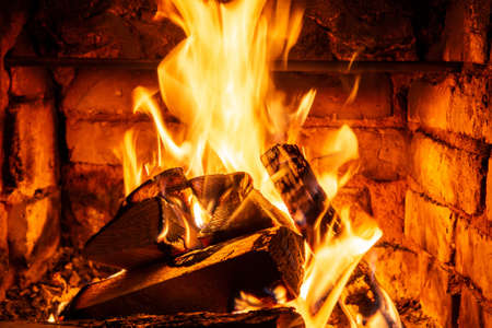 Firewood burning in fire burns in the fireplace. The brick oven gives heat and heat from the burnt logs. Burning coals and flames warm the apartment buildingの写真素材