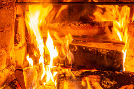 Firewood burning in fire burns in the fireplace. The brick oven gives heat and heat from the burnt logs. Burning coals and flames warm the apartment buildingの写真素材