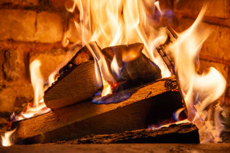 Firewood burning in fire burns in the fireplace. The brick oven gives heat and heat from the burnt...