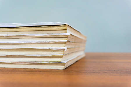 A stack of books are lying on a brown table, documents are stacked close-upの写真素材