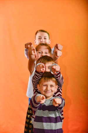 Four children stand in a row and point their fingers forward to the age on a yellow background, the...