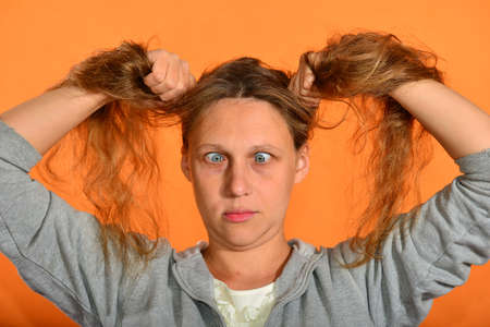 Surprised and crazy girl holding her hair with her hands on a yellow backgroundの写真素材
