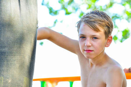 A boy in shorts boxing a pear with his hands in the open air.