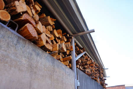 Sawed boards and logs for heating the stove, firewood stacked under a canopy
