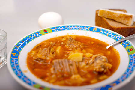 Red soup in a plate, a stack of vodka, boiled egg and lard with black bread are on the white table.の写真素材