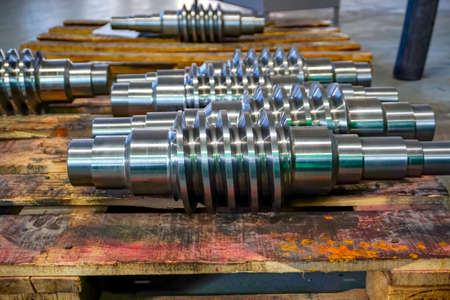 The worm shaft after machining lies on a wooden rack and is ready for use in mechanical engineering...