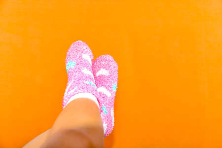Female legs in warm pink socks on orange background
