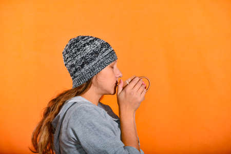 A woman in a knitted hat with a hot drink from a mug to keep warmの写真素材