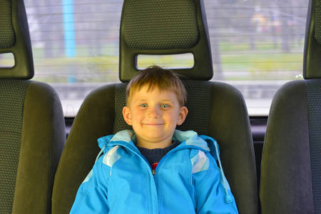 The boy is sitting in the back seat in the car