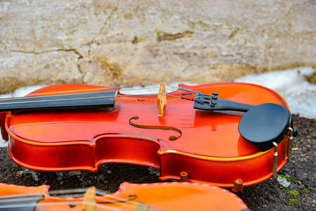 Two violins lie on the asphalt next to the snowの写真素材