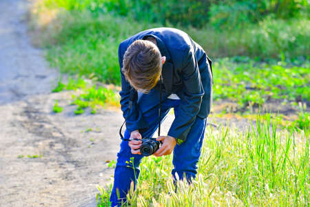 A boy with a camera walks down the street and takes pictures of wild flowers.の写真素材