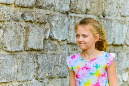 Young and beautiful girl posing against a brick wall on the street with a smile in a summer dress.の写真素材