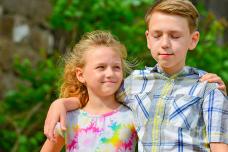 Brother and sister stand in an embrace in the park on the street and look at each other. The concept of happiness, family, love, unity and joy.の写真素材