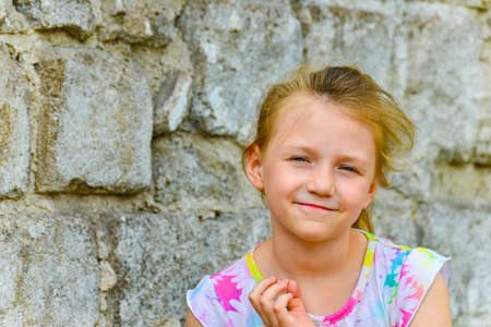 Young and beautiful girl posing against a brick wall on the street with a smile in a summer dress.の写真素材