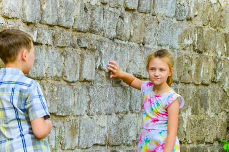 The boy is leaning against the brick wall, and the girl is posing for the camera on the street.の写真素材