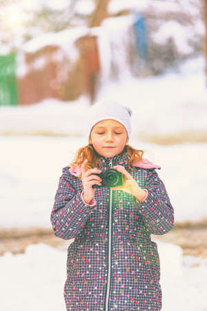 A girl walks in winter with a camera and takes pictures of sights in a snow-covered city.の写真素材