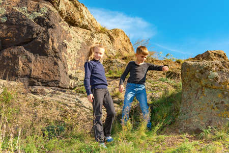 Brother and sister walk on the rocks, traveling through the mountains.の写真素材