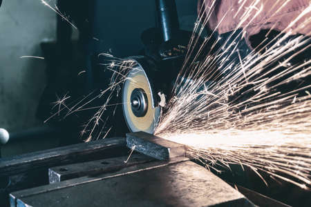 The working mechanic cleans the metal by grinding